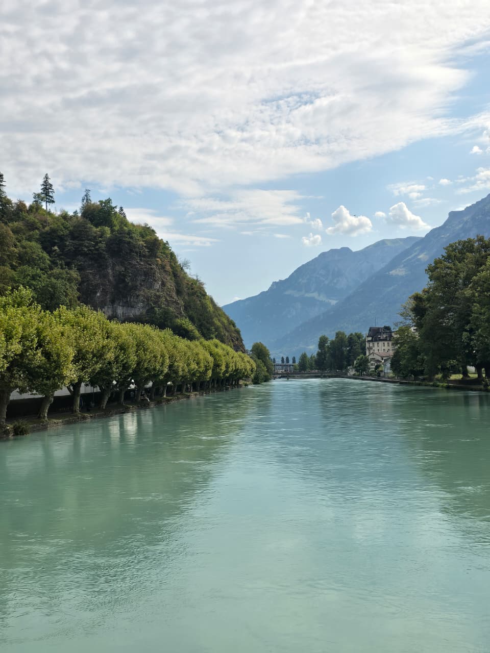Turquoise Aare river lined with trees in Interlaken