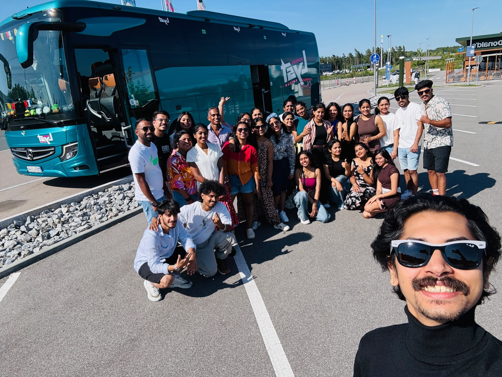 Selfie with the whole Prague tour group beside the teal Lyst coach at a rest stop