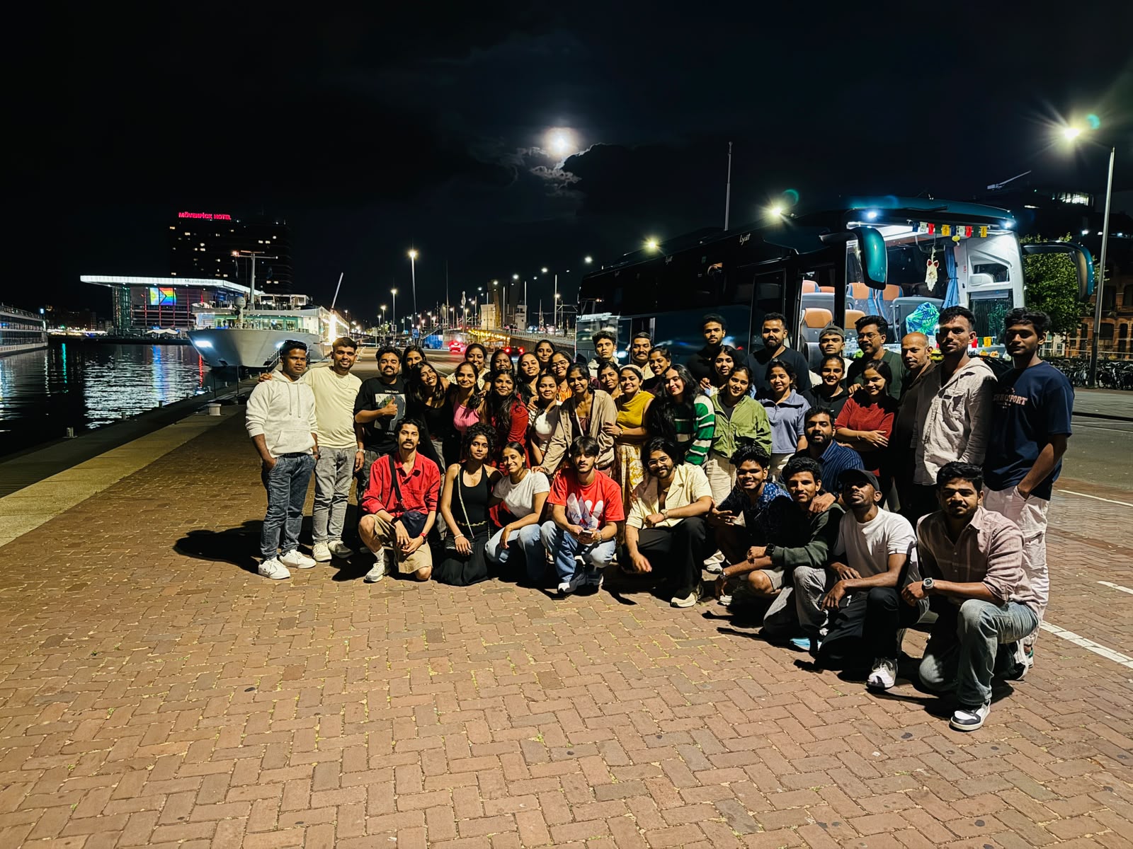 Full tour group beside the coach on the Amsterdam waterfront at night