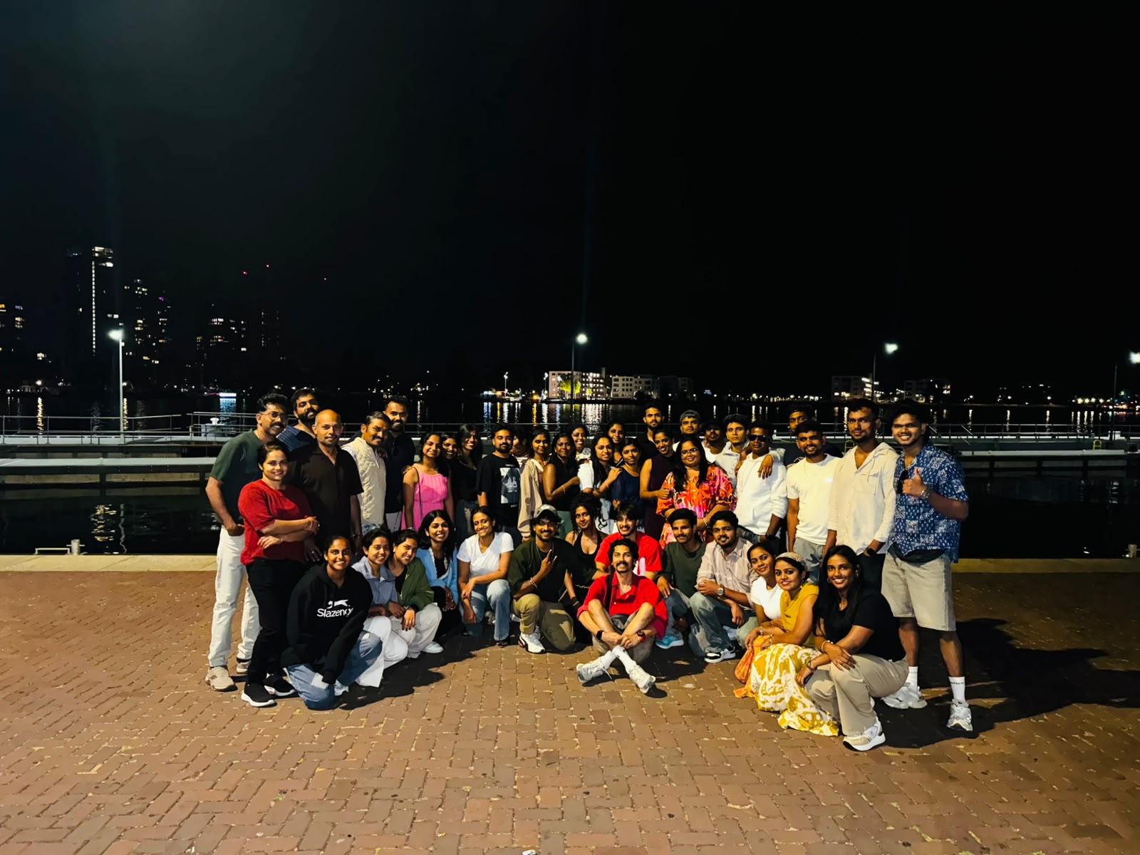 Night group photo by the water with the Amsterdam skyline behind