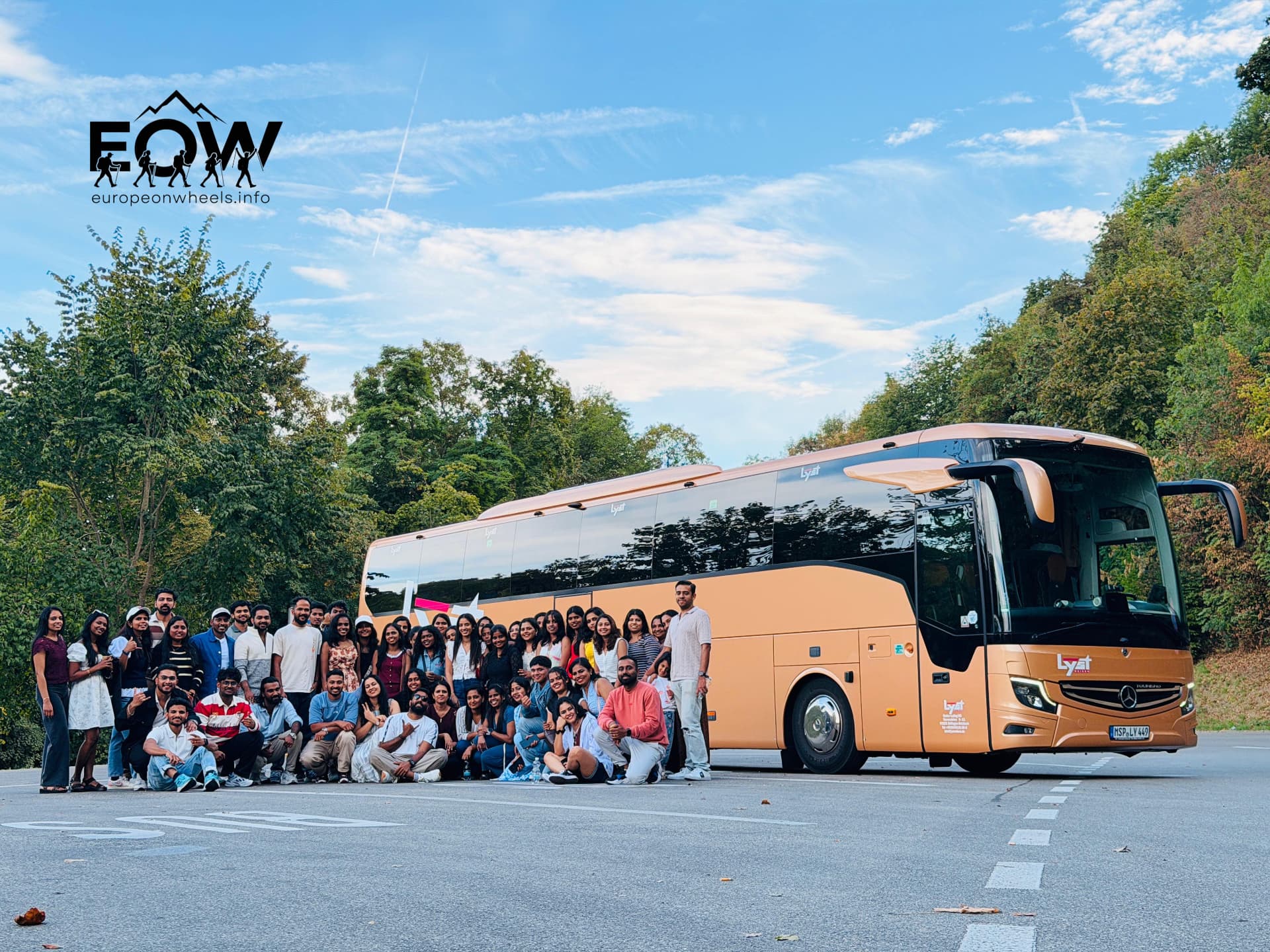 Smaller group photo with the gold coach and forested hillside in Switzerland