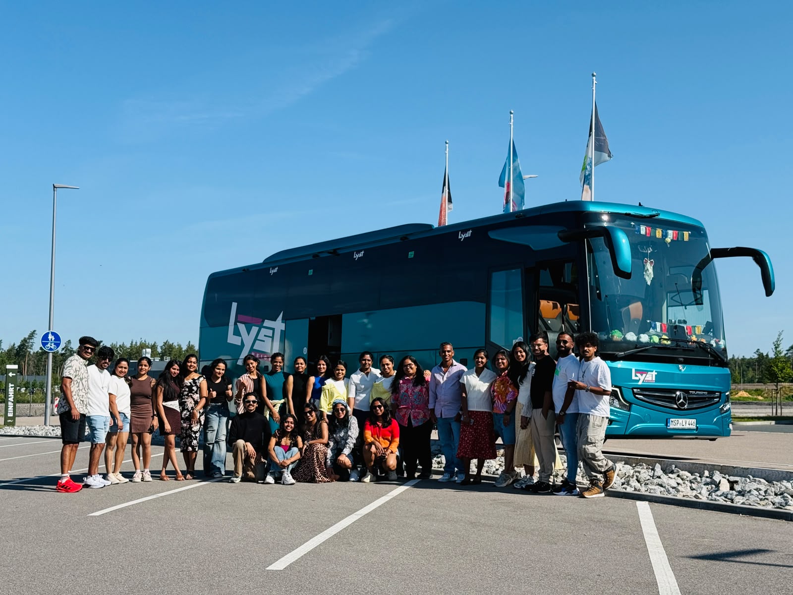 Prague travellers lined up in front of the teal Lyst coach under a clear blue sky
