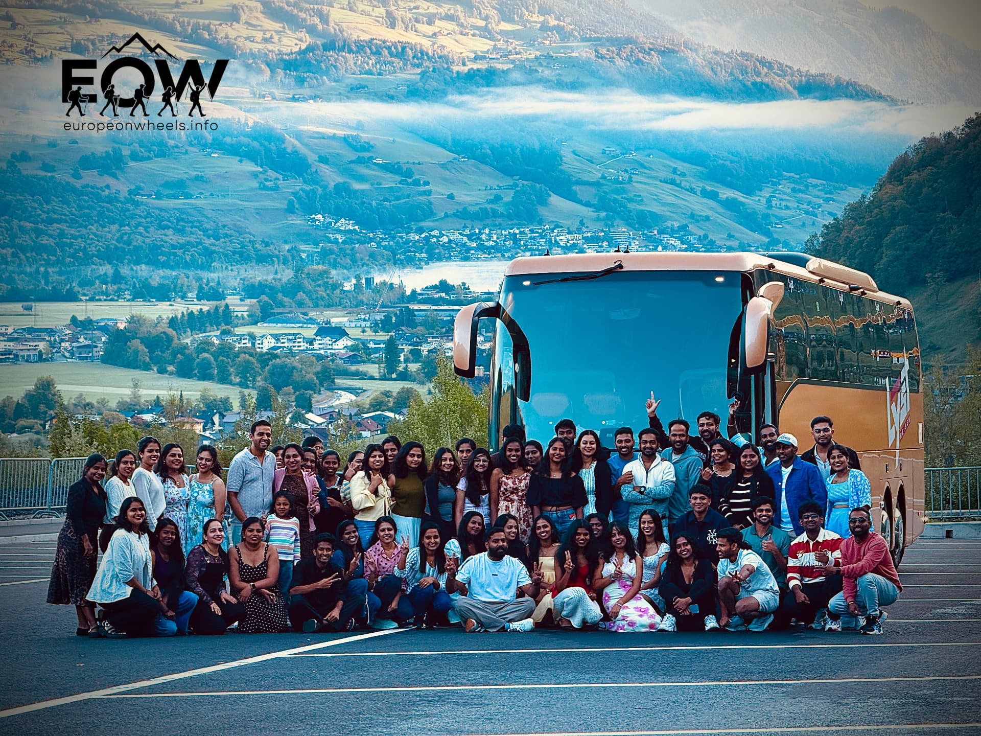 Large Europe on Wheels group photo with the gold coach and Swiss alpine valley behind