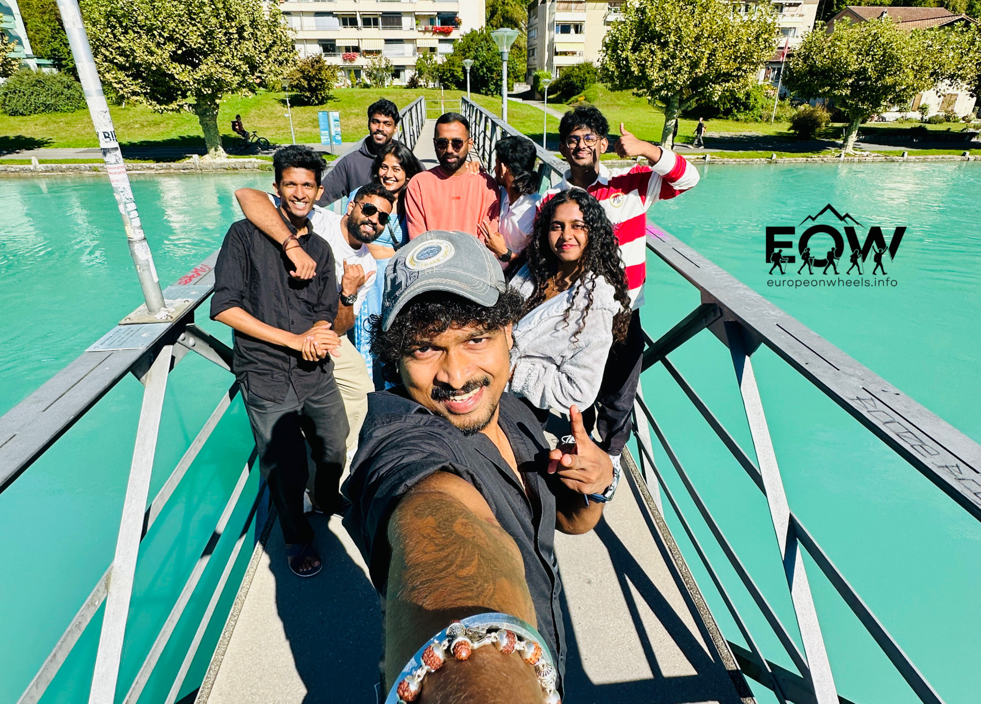 Group selfie on a footbridge over the turquoise Aare river in Interlaken
