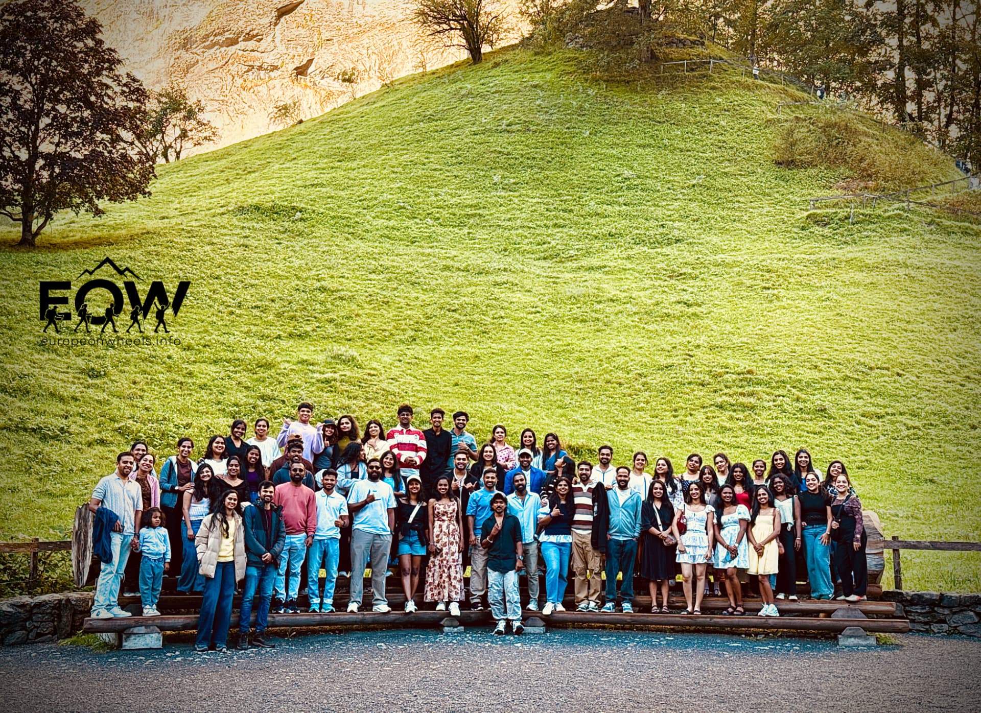 Full Europe on Wheels group photo on a green alpine hillside in Switzerland